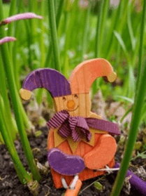 Wooden jester sat among flower stems